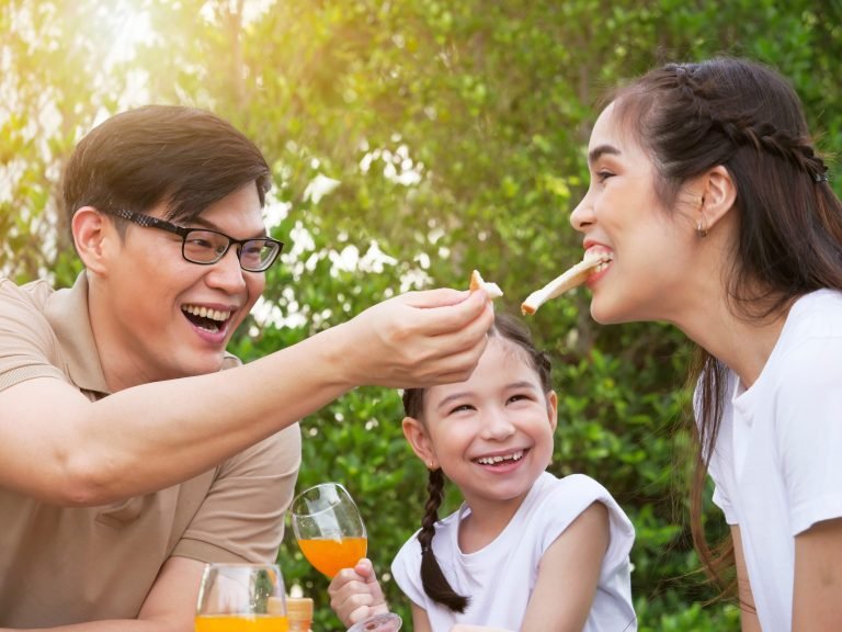 Happy young family enjoys feed food while camping outdoors