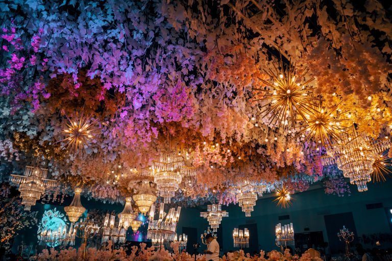 Scenic view of shiny chandeliers hanging on a ceiling surrounded by floral decorations