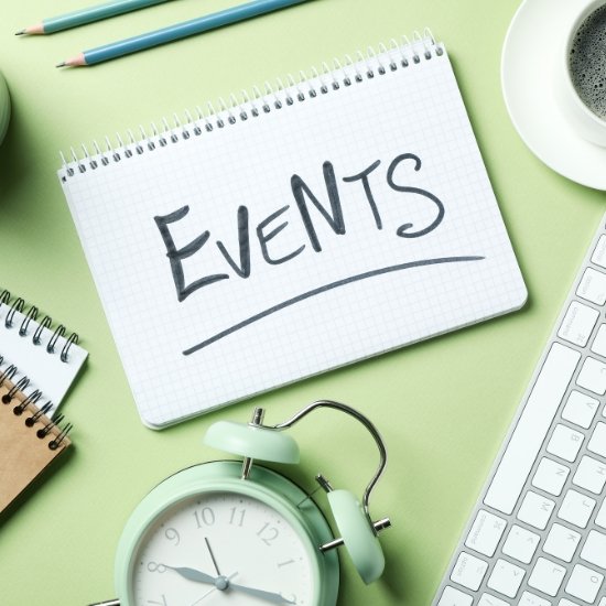 A top-down view of a desk with a keyboard, coffee, and a notepad with the word "EVENTS" written on it, representing the first stage of an event program flow in Quezon City.