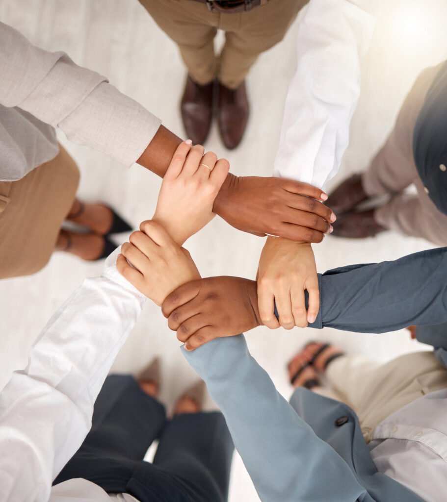 A diverse group of professionals joining hands in a circle, symbolizing unity and collaboration for an intimate wedding reception in Quezon City team or corporate event.