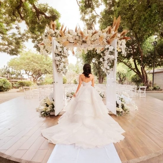 outdoor garden wedding ceremony in Quezon City with a floral door arch and white seating. This image offers inspiration for an outdoor wedding reception layout and Quezon City wedding seating arrangement ideas.
