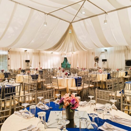 : Elegant tent wedding reception at Light of Love Trust venue with draped ceiling and blue table linens.