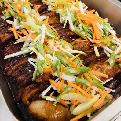 hizons-catering-braised-pork-belly-buffet Braised pork belly served on the buffet at Hizon's Catering, topped with fresh vegetables for weddings and special events.