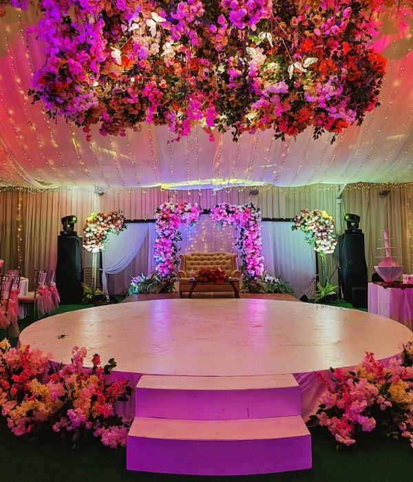 A stunning event stage in Quezon City with a circular white platform, pink floral overhead installations, and professional lighting, representing the final execution phase of a corporate event checklist.