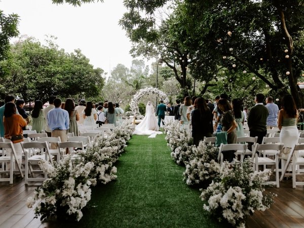 A beautiful outdoor garden ceremony at a wedding venue in Quezon City, featuring white guest seating and a floral archway.